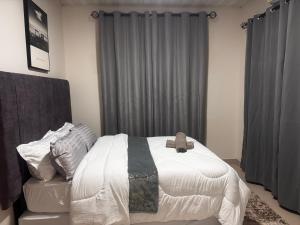 a bedroom with a white bed and gray curtains at Kaya Apartment 3 in Lusaka
