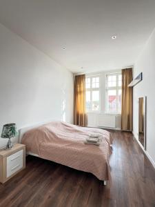 a bedroom with white walls and a bed and wooden floors at Long Island in Grudziądz