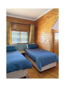 two beds in a room with wooden walls at Rihla Residences - Civic Road in Cape Town