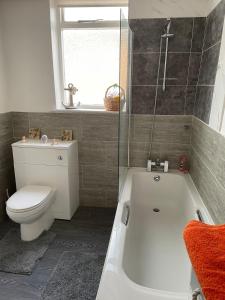 a bathroom with a tub and a toilet and a window at Large 4 bedroom house in Heckington +18 photos