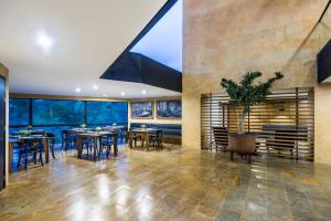 a dining room with tables and chairs and a large window at Travelers Rio Verde Living Suites in Rionegro