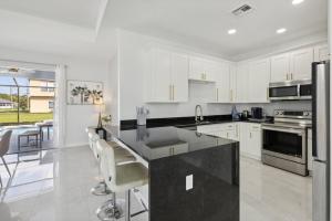 Una cocina con gabinetes blancos y una encimera negra. en Lomb CT, en Port Saint Lucie 5 fotos más