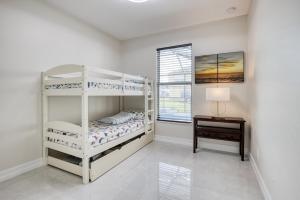 Un dormitorio con dos literas y una mesa. en Lomb CT, en Port Saint Lucie