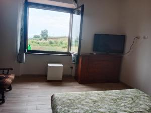 a bedroom with a bed and a tv and a window at Qui vive un sogno in Roccastrada