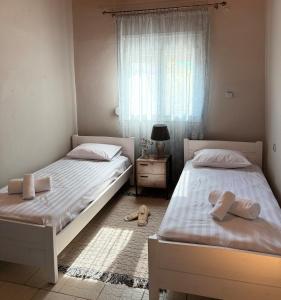 two beds in a bedroom with a window and shoes on the floor at Serenity home Salamina in Áyios Yeóryios