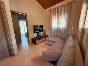 a living room with a couch and a flat screen tv at Serenity home Salamina in Áyios Yeóryios