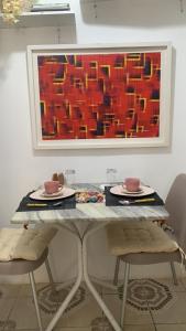 a table with two chairs and a painting on the wall at Pousadinha Mel -DORMITÓRIOS in Salvador +21 photos