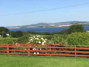 einen Holzzaun mit Blick auf das Wasser in der Unterkunft Swilly View House in Ramelton