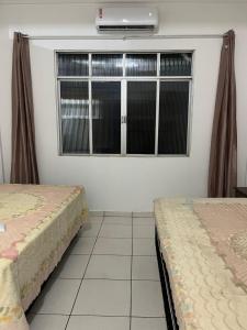 two beds sitting in a room with a window at Casa simples e conforto in Belém