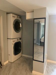 een wasruimte met wasmachine en droger naast een spiegel bij A Cozy Corner with kitchen and parking in Drexel Hill