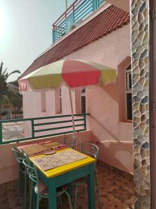 a table and chairs with an umbrella on a balcony at Riad dar MUMTI in Saïdia +20 photos