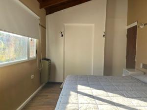 a bedroom with a bed and a window and a door at Hostería Las Rosas Trevelin in Trevelín