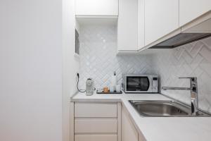 a white kitchen with a sink and a microwave at Duomo Area Luxury Design & Netflix Mood in Milan