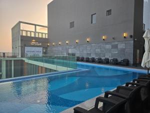 釜山premium ocean view in HAEHUNDAE BONA TRAVEL的一个带椅子的大型游泳池和一栋建筑