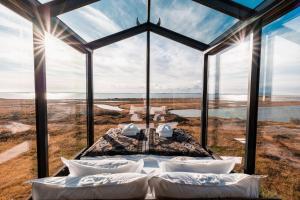 Panorama Glass Lodge WEST في أكرانيس: غرفة نوم بنوافذ كبيرة وسرير بمخدات بيضاء