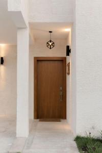 a wooden door in a white building with a light fixture at House of Flores Villa Bavaro in Punta Cana