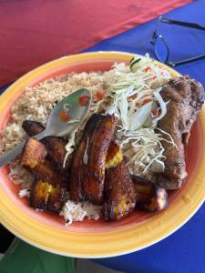 a plate of food with meat and rice on a table at Miss Miriam BeachFront Cabins in Tortuguero