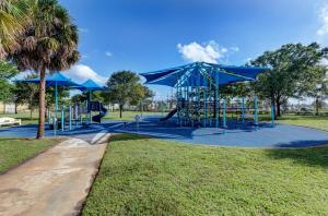a playground in a park with blue umbrellas at Charming West Palm Beach Home in West Palm Beach