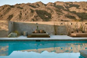 Una piscina con dos camas al lado de una montaña. en RESET Hotel Joshua Tree, en Twentynine Palms