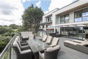 a patio with a glass table and chairs on a balcony at Creek view house in Feock