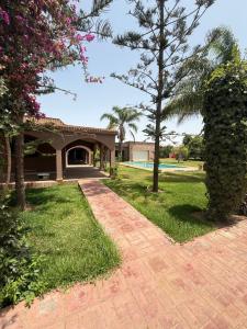 a brick walkway in front of a house with trees at Chic home with a private pool in Dar Mouddene
