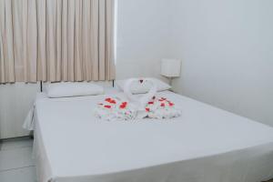 un lit blanc avec des draps blancs et des fleurs dessus dans l'établissement Apto 1203 - Golden Dolphin SUPREME, à Caldas Novas