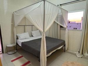 a bedroom with a canopy bed with a window at La Maison des Couleurs in Dakar +41 photos