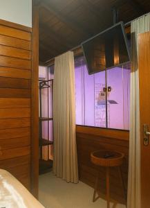 a bedroom with a bed and a large window at La Playa Bangalô in Arraial d'Ajuda