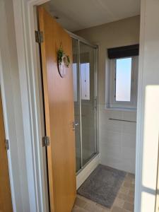 a bathroom with a shower and a glass door at Spacious & Homely Colchester Stay-Great Location in Hythe