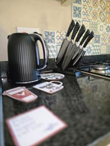 a black counter top with a coffee pot and utensils at Spacious & Homely Colchester Stay-Great Location in Hythe