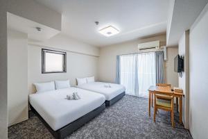 una camera d'albergo con due letti e una scrivania di LABEL 01 Dotonbori Aparthotel ad Osaka