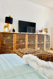una camera da letto con televisore su un centro di intrattenimento in legno di Appartement vue panoramique mer et piscine a Sainte-Anne