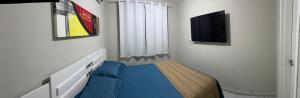 a small bedroom with a blue bed and a tv at Apto 02 Quartos Mobiliado na Praia do Poço - CABEDELO in Cabedelo