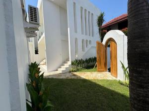 a white building with a wooden door in a yard at Nelayan Reef Apartment in Mantaak