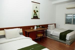 a room with two beds and a table and a desk at Arawa Traveller's Inn Motel in Makassar