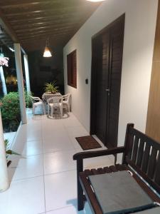 a porch with a black door and a bench at Flat Xareuzinho - Praia Antunes in Barra Grande