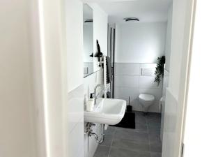 a white bathroom with a sink and a toilet at City-Apartment für Familien 5 Per, 8 Min zum Hbf! in Mönchengladbach +8 photos