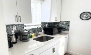 a white kitchen with a sink and a microwave at The Madison by the Gold Nests in Hollywood +177 photos