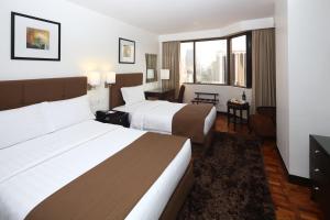 een hotelkamer met twee bedden en een bureau bij City Garden Hotel Makati in Manilla