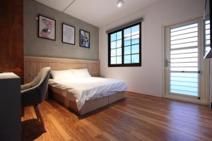 una camera da letto con un letto, una scrivania e due finestre di G.O.A.T Hostel a Città di Hualien