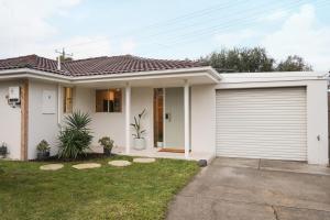 a white house with a garage at Capel Sound Beach House Steps to Sand in Capel Sound