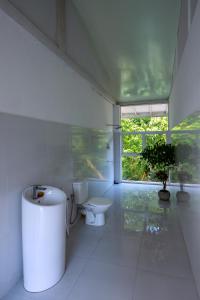 ein weißes Bad mit einem WC und einem Fenster in der Unterkunft Tea Heritage in Urulewatta