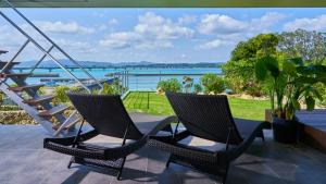 two chairs on a patio with a view of the water at オーシャンフロントKouri Stay in Nakijin