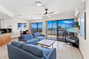 a living room with two blue couches and a tv at Whiskey on Orana in Airlie Beach