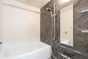 a bathroom with a white tub and a shower at Daffitto Honjo Azumabashi in Tokyo