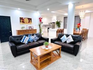 un soggiorno con due divani in pelle e un tavolo di Taylors Plantacion Resort- Grande Ground Floor a Tangaro