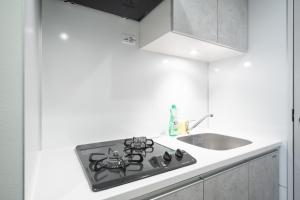 a white kitchen with a stove and a sink at Daffitto Honjo Azumabashi in Tokyo