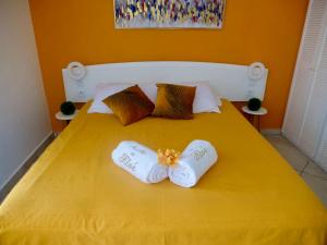 un letto giallo con due asciugamani sopra di Au Nid de KLOE, plage & piscine a Grand-Bourg