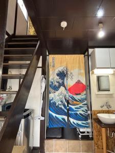 a door with a painting of a wave in a kitchen at ワカバハウス in Wada