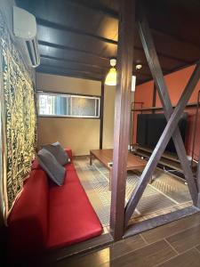 a living room with a red couch and a tv at ワカバハウス in Wada